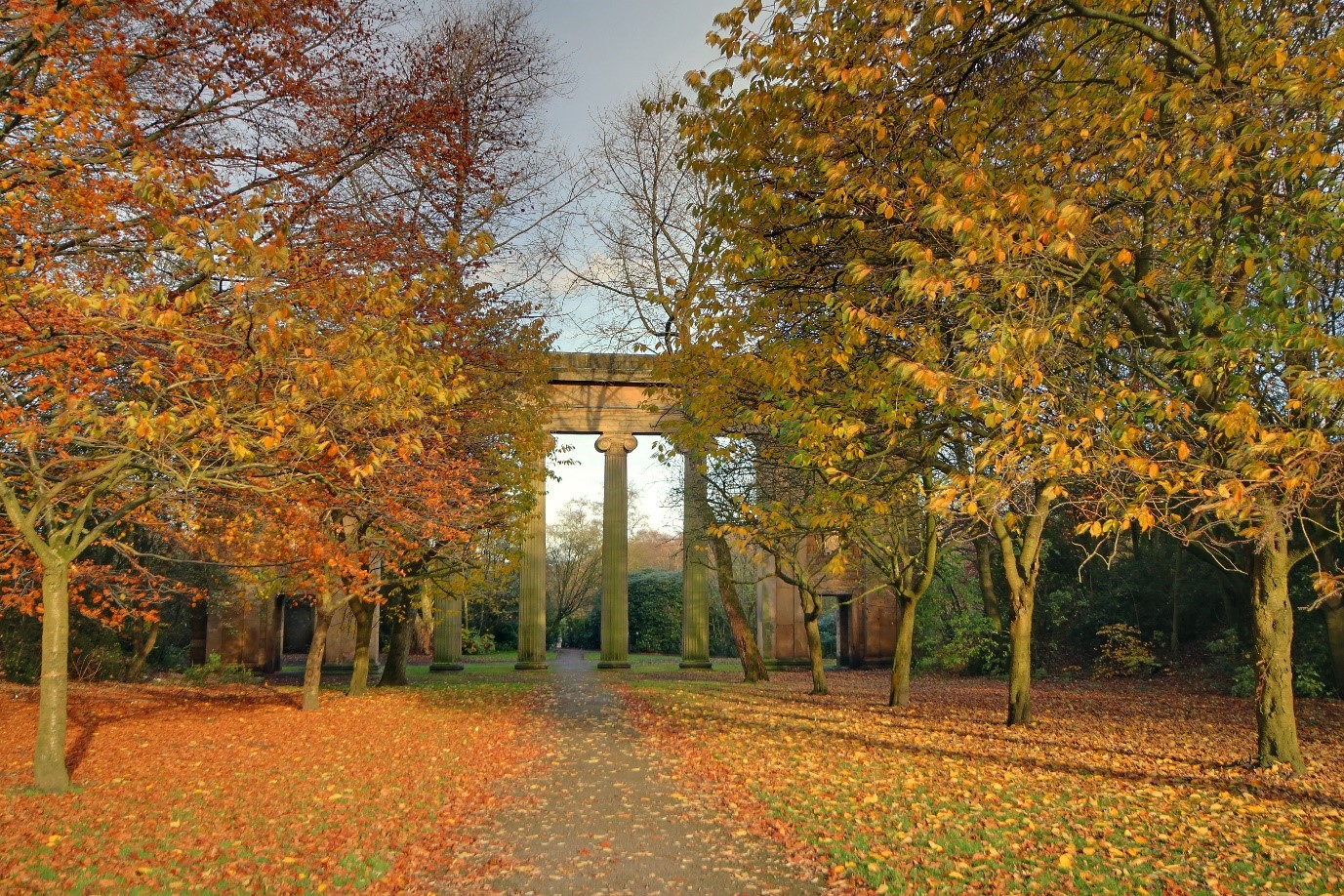 heaton park the stone arch surounded by an ave of trees and open green spaces