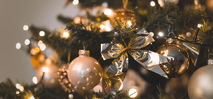 a close up of a christmas tree with yellow lights and gold bows and christmas ornaments