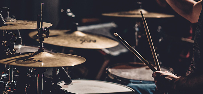 a close up of a drum set and two drumsticks in a man's hand on stage