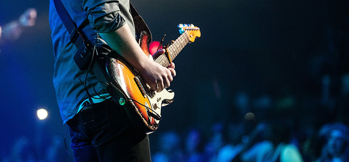 a man on stage playing guitar with a large crowd behind him