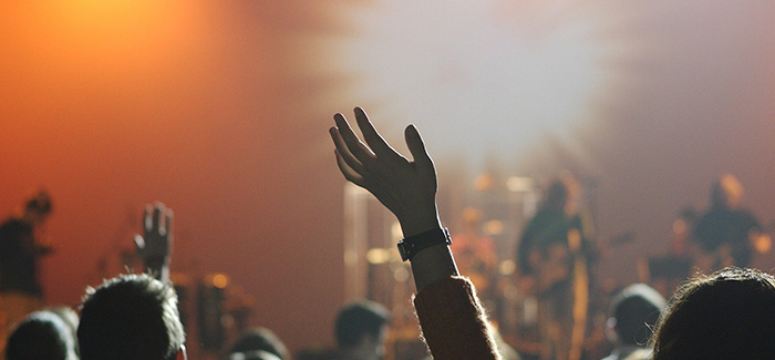 a large crowd cheering a band that is on stage in a nightclub