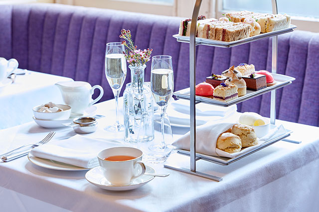 a table with glasses of champagn, tea and a stand full of different types of pasteries
