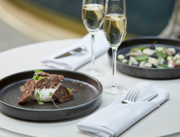 two glasses of champagne alongside two meals 